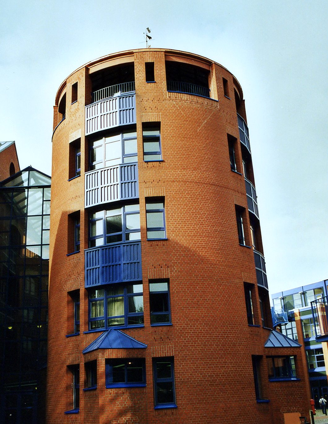 Sanierter runder Klinkerturm mit blauen Fenstern und Balkonbrüstungen