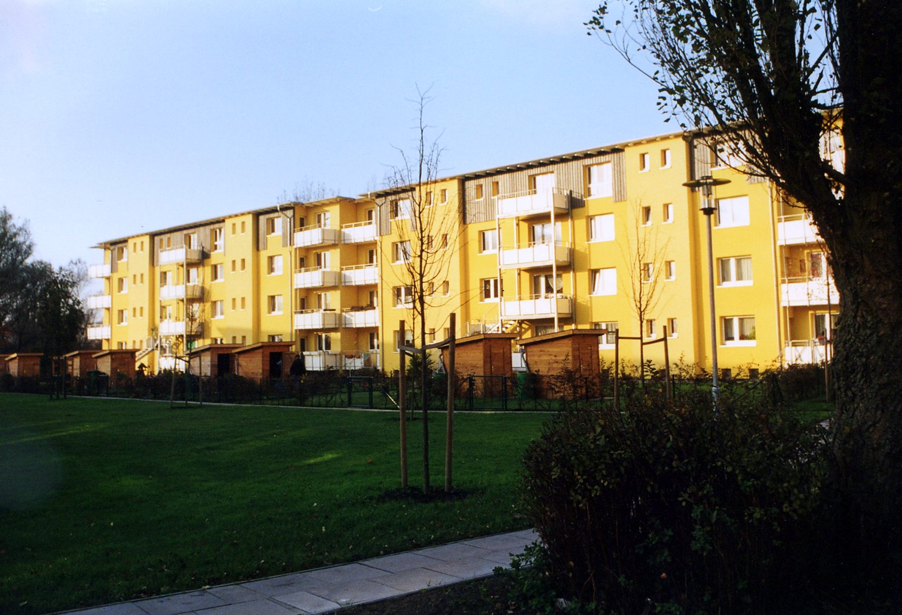 Sanierte Wohnzeile mit gelber Putzfassade und neuen Balkonen